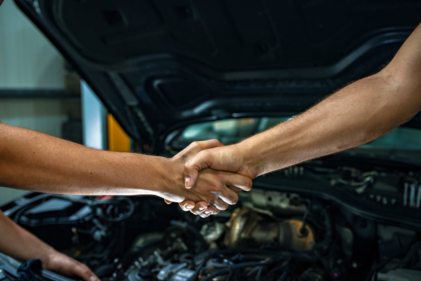 Car mechanic handshakes customer